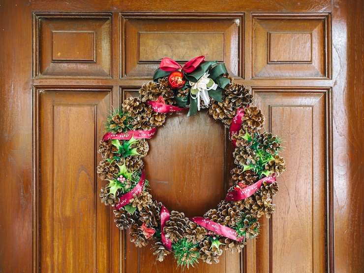 La decoración de la corona de Navidad está colgada en la puerta de madera.
