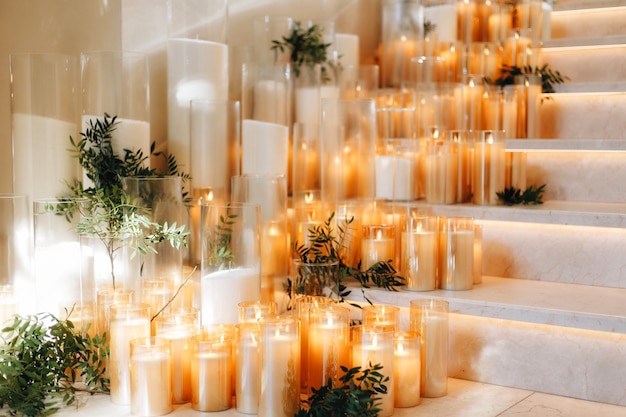 Decoración de diseño de mesa de boda romántica con grandes ramos de flores exuberantes que incluyen rosas blancas, ranúnculos, ranúnculos persas, orquídeas blancas y velas. Foto de alta calidad