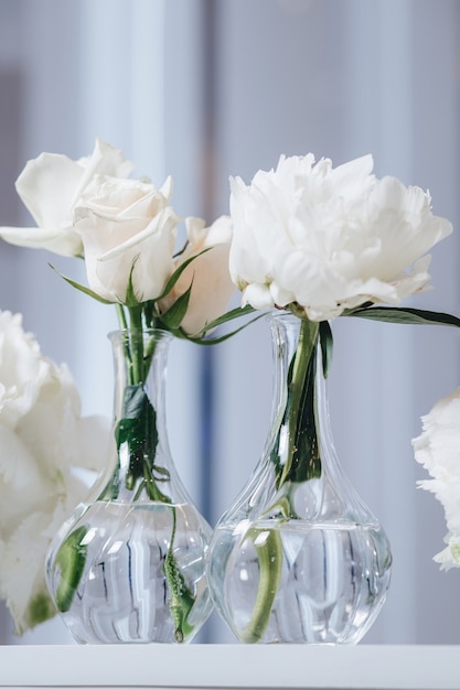 Decoración de diseño de mesa de boda romántica con grandes ramos de flores exuberantes que incluyen rosas blancas ranunculus ranúnculos persas orquídeas blancas y velas