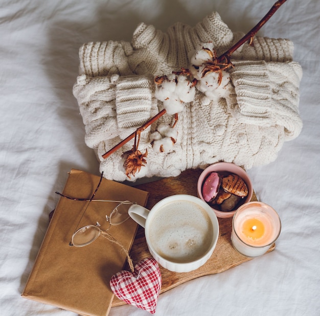 Decoración ecológica para el hogar. Decoración acogedora para el hogar. Una taza de capuchino, galletas, una vela en la cama. Mañana de invierno. Vacaciones.