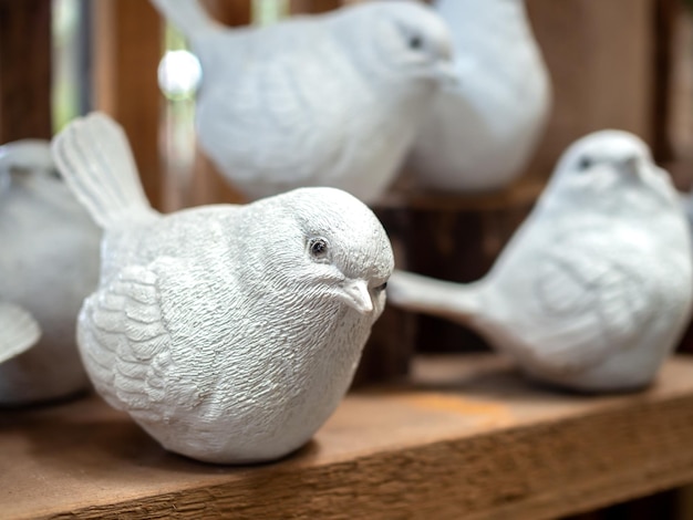 Decoración de escultura de pájaro de mortero realista blanco sobre fondo de madera