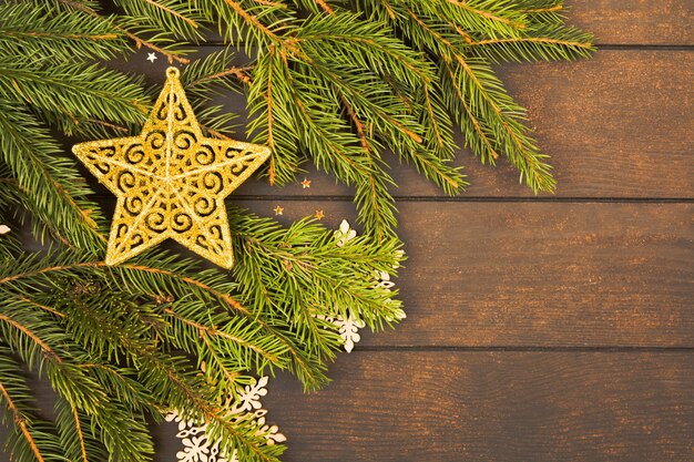 Decoración de estrella de navidad dorada en ramas de abeto sobre fondo de madera con espacio de copia