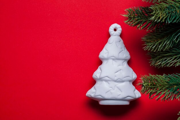 Decoración festiva del árbol de Navidad blanco sobre un fondo rojo.