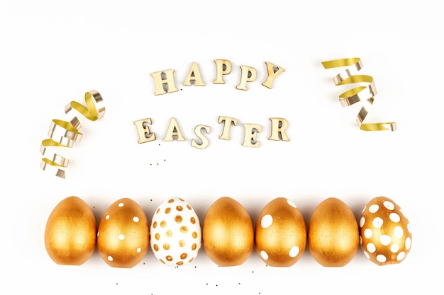 Decoración festiva de Pascua. Vista superior de los huevos de Pascua coloreados con pintura dorada e inscripción en inglés Happy Easter.