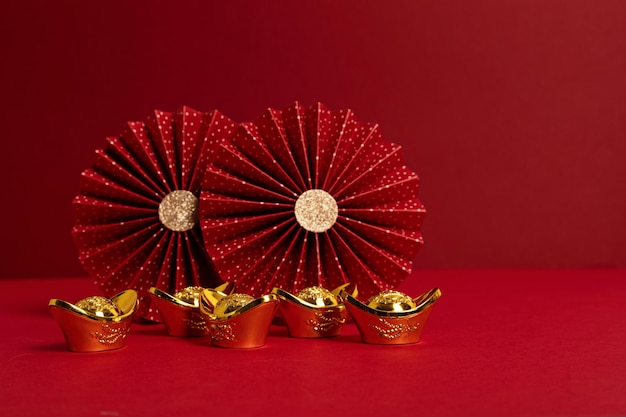 Decoración del festival de año nuevo chino sobre fondo rojo. lingotes de oro tradicionales del año nuevo lunar, abanicos de papel. Copia espacio