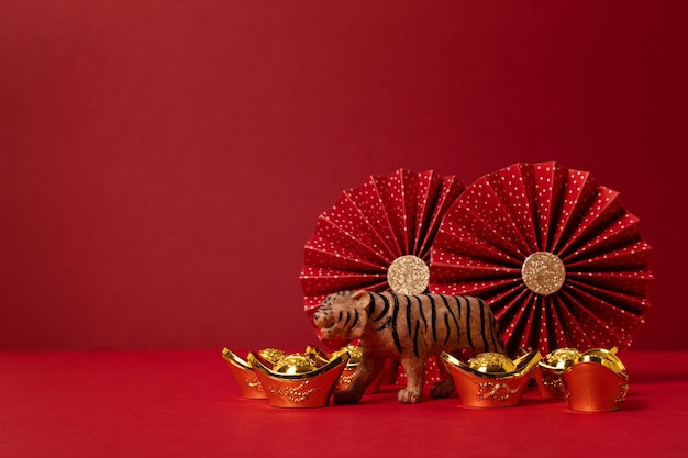 Decoración del festival de año nuevo chino sobre fondo rojo. lingotes de oro tradicionales del año nuevo lunar, abanicos de papel, tigre. Copia espacio