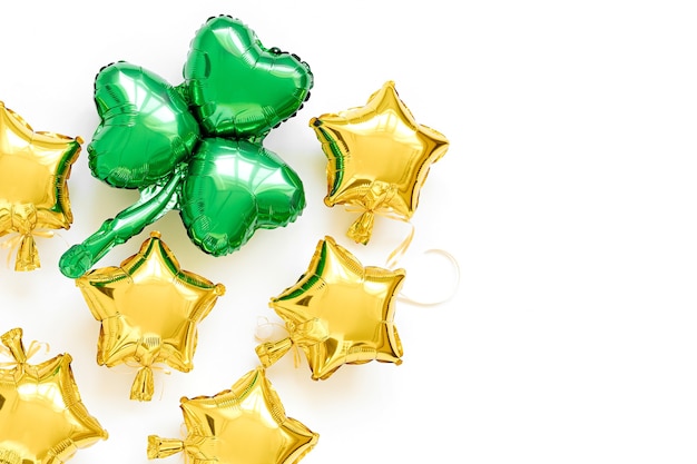 Decoración de la fiesta del Día de San Patricio. Globos de lámina de oro con formas de estrellas y globos verdes con forma de hoja de trébol. Concepto de vacaciones y celebración. Globos de aire metálicos.