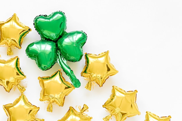 Decoración de la fiesta del Día de San Patricio. Globos de lámina de oro con formas de estrellas y globos verdes con forma de hoja de trébol. Concepto de vacaciones y celebración. Globos de aire metálicos.