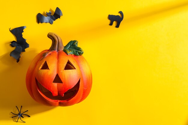 Decoración para fiesta de Halloween con farolillo de calabaza y murciélagos cortados artesanalmente, gato y araña sobre fondo amarillo