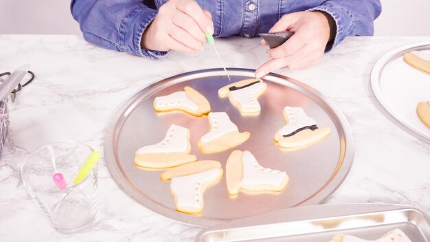 Decoración de galletas de azúcar en forma de patines de hielo con glaseado real de color blanco.