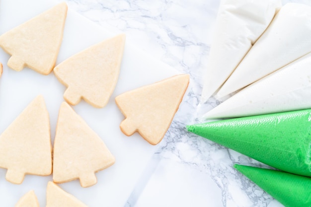 Decoración de galletas de azúcar navideñas con glaseado real y chispas.