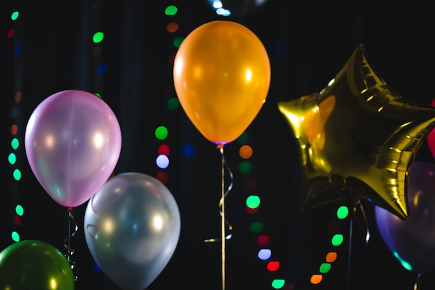 Decoración de globos de colores para fiesta, celebración de fin de año. fiesta de navidad, globo en fondo negro, globos de helio, naranja, verde, azul y morado.