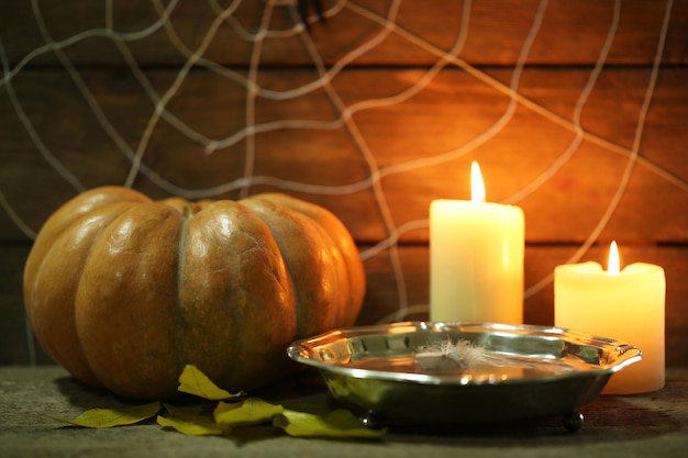 Decoración de Halloween con araña en web calabaza y velas sobre fondo de madera