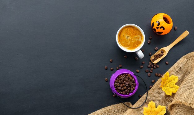 Decoración de Halloween con café caliente y frijoles sobre fondo oscuro. endecha plana. Copie el espacio para el texto.