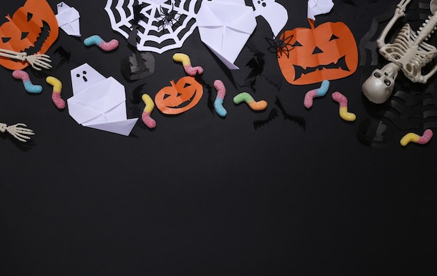 Decoración de Halloween hecha a mano y esqueleto, gusanos de goma sobre fondo negro. Fondo de Halloween. Copie el espacio. Vista superior. Endecha plana