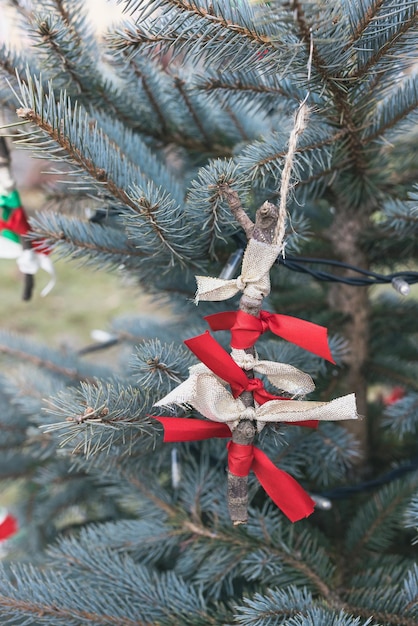 Decoración hecha a mano de bricolaje con palitos y cintas en el árbol de Navidad