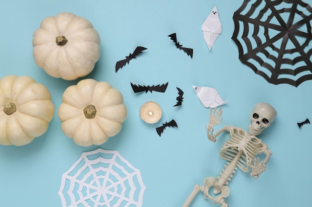 Foto decoración hecha a mano de halloween esqueletos y calabazas sobre fondo azul vista plana lay top