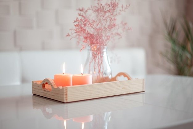 Foto decoración del hogar bandeja de madera con cadles y flores secas rosas sobre la mesa blanca