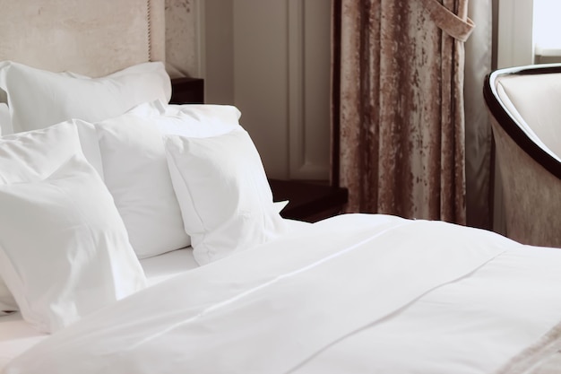 Decoración del hogar y cama de diseño de interiores con ropa de cama blanca en el dormitorio de lujo servicio de lavandería de ropa de cama y detalle de muebles