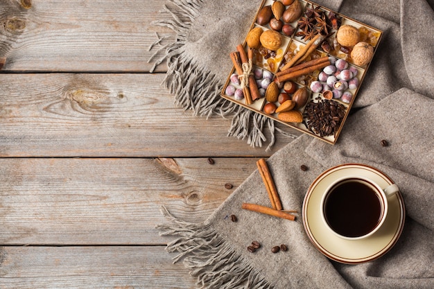Decoración del hogar de otoño, otoño e invierno en estilo escandinavo, Hygge. Composición de temporada con taza de café, cálida bufanda de lana, cuadros suaves sobre una mesa de madera rústica.