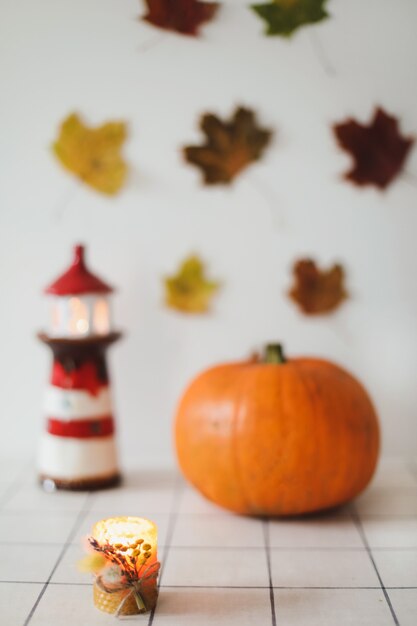 Decoración del hogar de otoño con una vela en candelabro de hojas secas sobre fondo blanco.