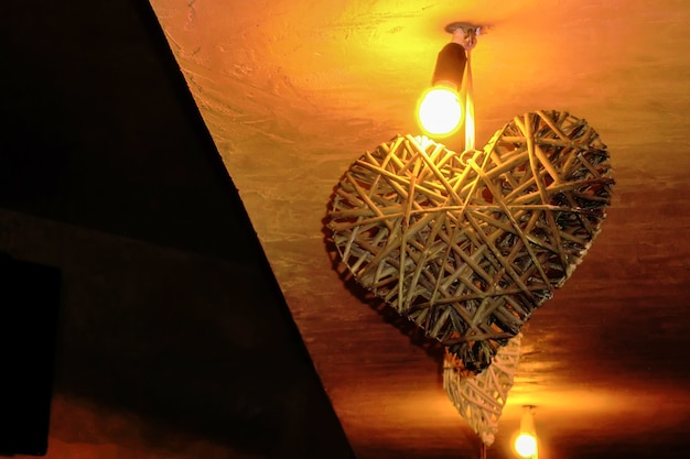 Foto decoración interior en forma de corazón pegada al techo de una habitación, iluminada por una lámpara encendida.