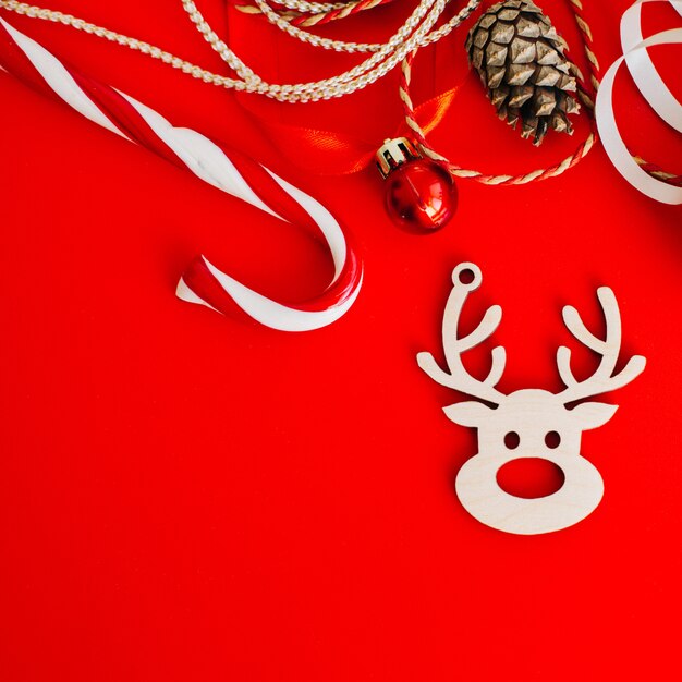 Decoración de madera en el árbol de Navidad en forma de un reno sobre un fondo rojo