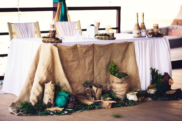 Decoración de mesa de boda en estilo rústico con arpillera, tocones, velas, vegetación.