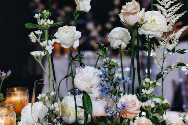 Decoración de mesa de boda romántica con grandes ramos de flores exuberantes que incluyen rosas blancas ranunc ...