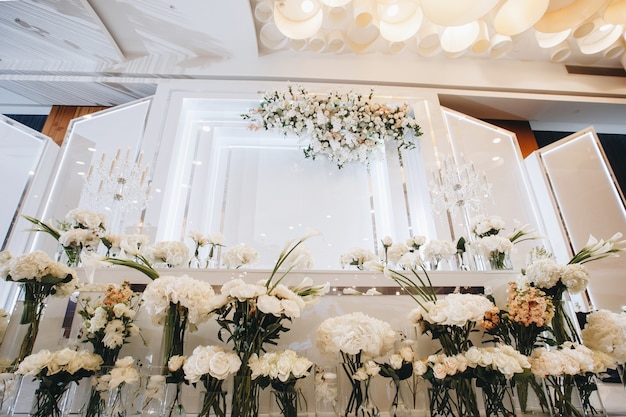 Decoración de mesa de boda romántica con grandes ramos de flores exuberantes que incluyen rosas blancas ranunc ...