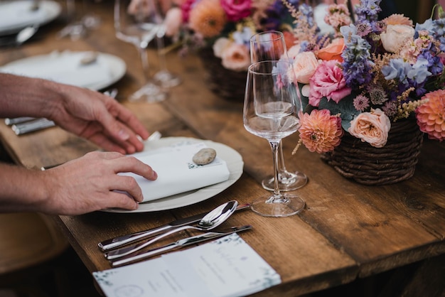 Decoración de la mesa de bodas con flores y rosas y plato con manos humanas