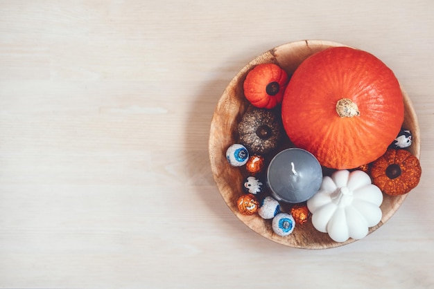 Decoración mínima de vacaciones de halloween con calabazas, dulces, velas negras en una mesa de madera en el interior