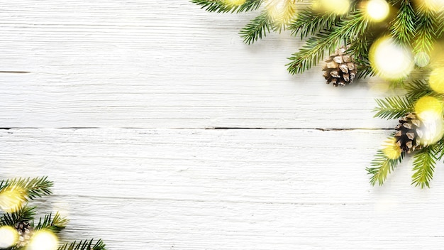 Decoración de Navidad y año nuevo sobre fondo blanco de madera con ramas de abeto y brillantes luces doradas.