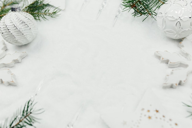Decoración de Navidad blanca y ramas de abeto en la nieve, fondo de Navidad blanca, bolas de Navidad blancas.