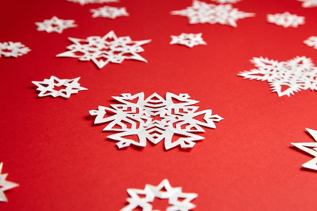 Decoración de Navidad con copos de nieve de papel blanco sobre fondo rojo.