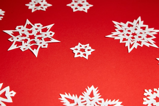 Decoración de Navidad con copos de nieve de papel blanco sobre fondo rojo.