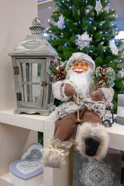 Decoración de Navidad Santa Claus sentado cerca de un árbol de Navidad con una linterna para velas. Composición navideña. Juguete de Navidad Santa Claus.