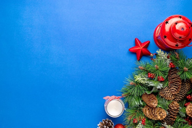 Decoración de Navidad en superficie azul Ramas de abeto con piñas Vela y linterna al lado