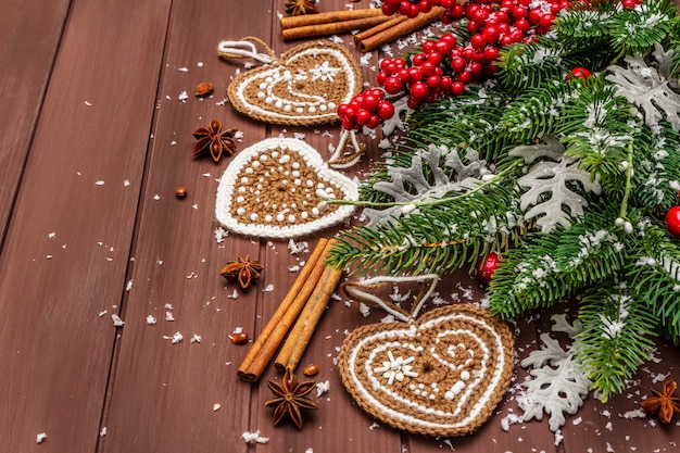 Decoración navideña. Abeto de año nuevo, hojas frescas, galletas de jengibre de ganchillo corazones, especias y nieve artificial.