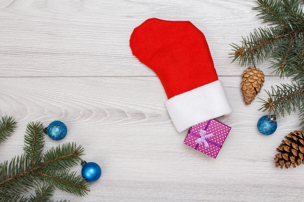 Decoración navideña. Bota de Papá Noel, caja de regalo, ramas de abeto con conos y juguetes navideños sobre tablas de madera gris. Vista superior. Concepto de tarjeta de felicitación de Navidad.