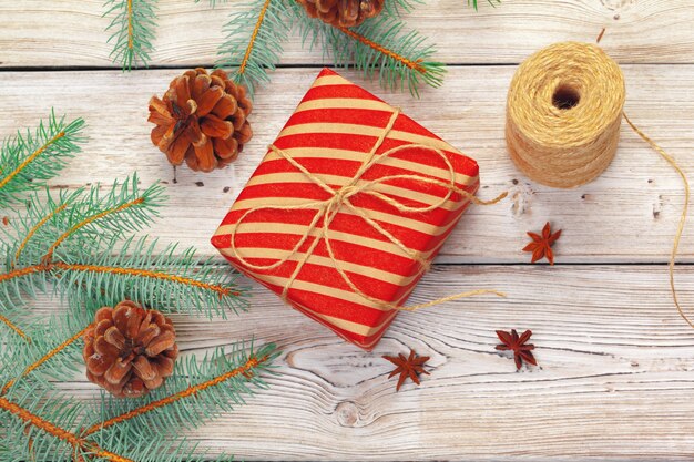 Decoración navideña, caja de regalo y ramas de pino en mesa de madera