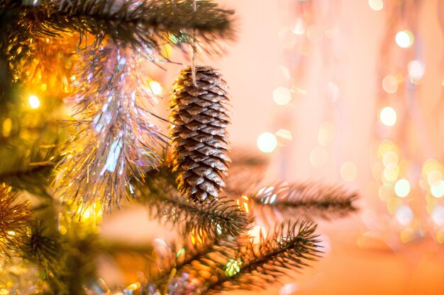 Decoración navideña en el cono de abeto del árbol de navidad con oro alrededor de boke