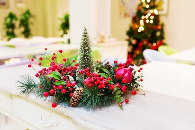 Decoración navideña: corona con ramas de abeto, frutos rojos y piñas.