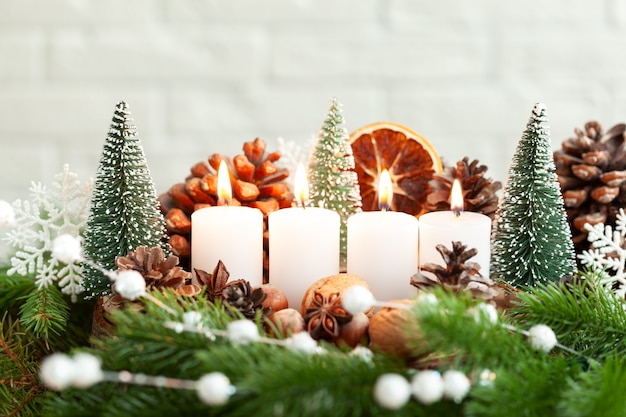 Decoración navideña cuatro velas encendidas en la víspera de Navidad y decoración natural de ramas de abeto con adorno navideño.