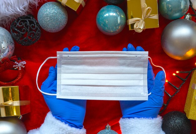 Decoración navideña con guantes médicos azules y mascarilla protectora para COVID-19, plano