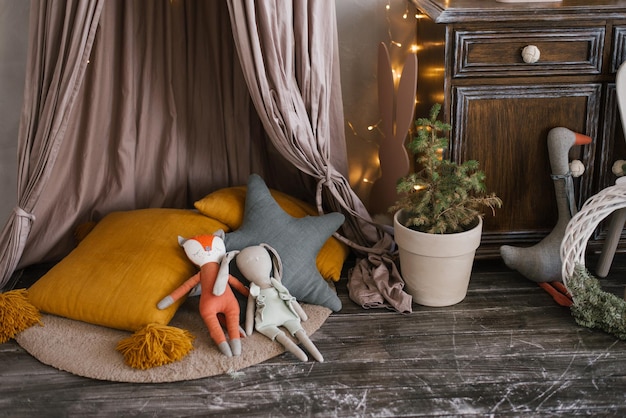 Decoración navideña en la habitación de los niños juguetes un árbol en una maceta una corona navideña almohadas y luces