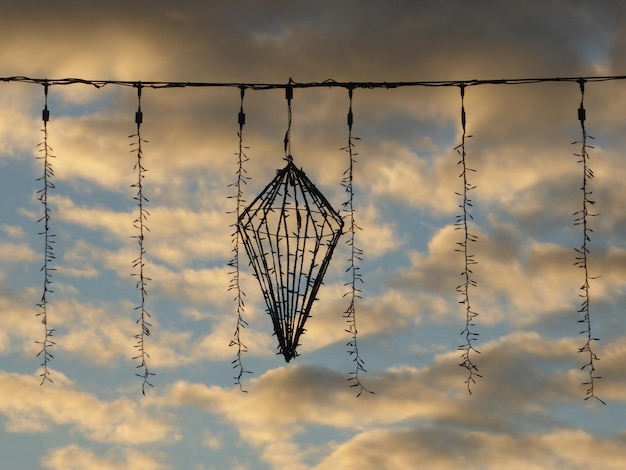 Decoración navideña con luces en el cable contra el cielo nublado