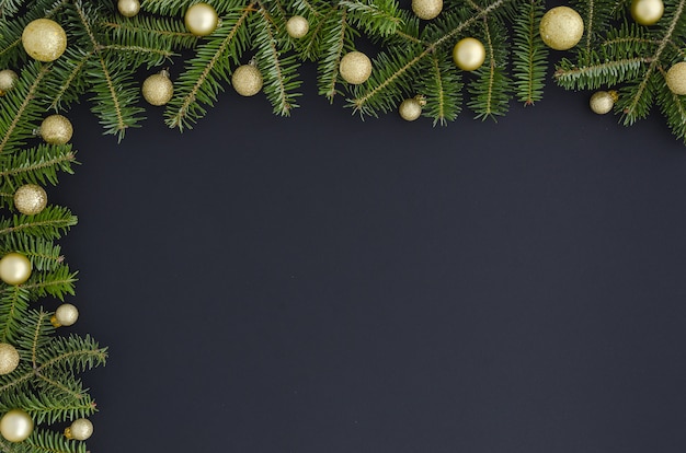 Decoración navideña o de Año Nuevo: ramas de árbol de pieles, bolas doradas sobre fondo negro, copia