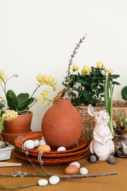 Decoración navideña de Pascua Narcisos y jacintos en una olla huevos y una figura de conejo y ramas en jarrones