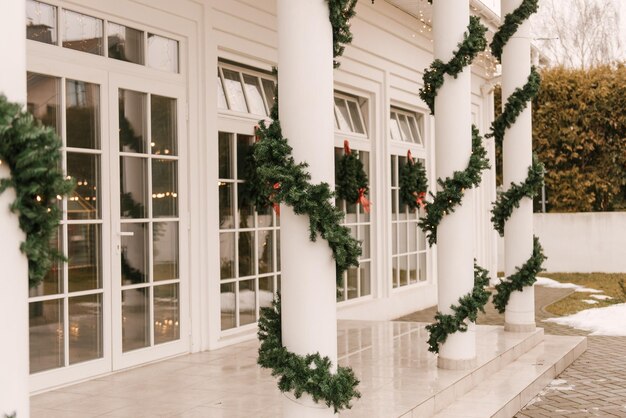 Decoración navideña del porche de una gran casa blanca con un abeto